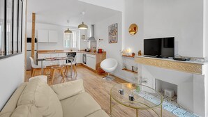 A modern living room with a sofa, a glass coffee table, and a TV. - LA PARENTHÈSE - Charmant T2 entièrement rénové (Toulouse)