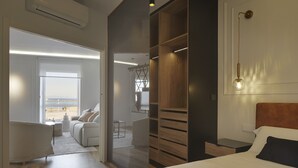 A modern hotel room with a large bed, a wooden wardrobe, a desk, and a view of the beach through the window. - Always Easy I Sagües (San Sebastián/Donostia)