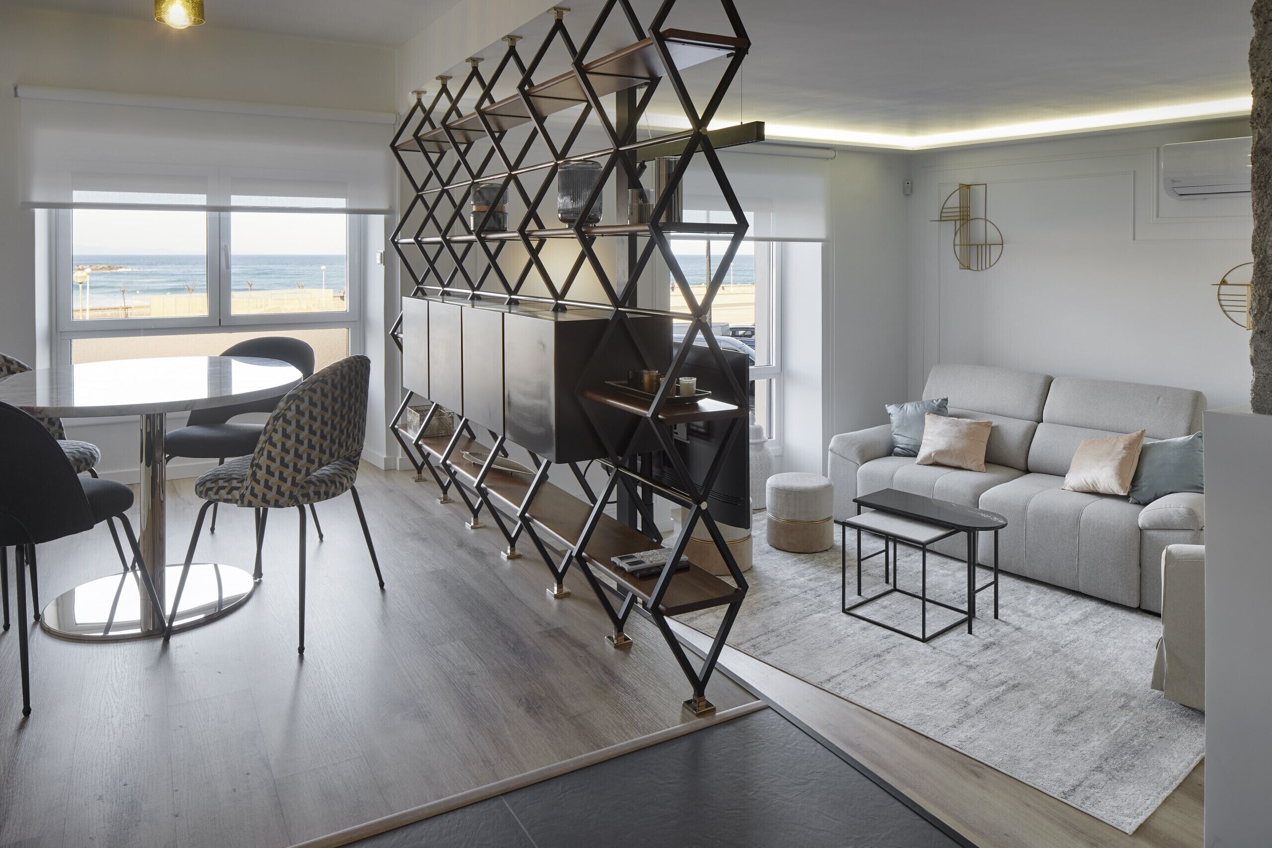 A modern living room with a sofa, coffee table, and a geometric shelving unit.