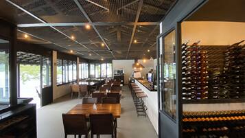 En rymlig restaurang med högt i tak, en lång bardisk och ett vinställ fullt med flaskor.