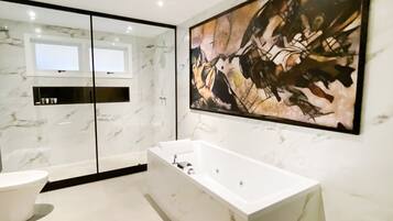 A modern bathroom with a large bathtub, a toilet, and a mirror.
