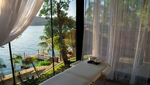 A spa area with a massage table, a view of the sea, and a tropical garden. -  Pousada Papiro Boutique (Angra dos Reis)