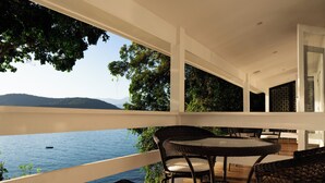 A balcony with a view of a body of water and mountains, furnished with wicker chairs and a table. -  Pousada Papiro Boutique (Angra dos Reis)