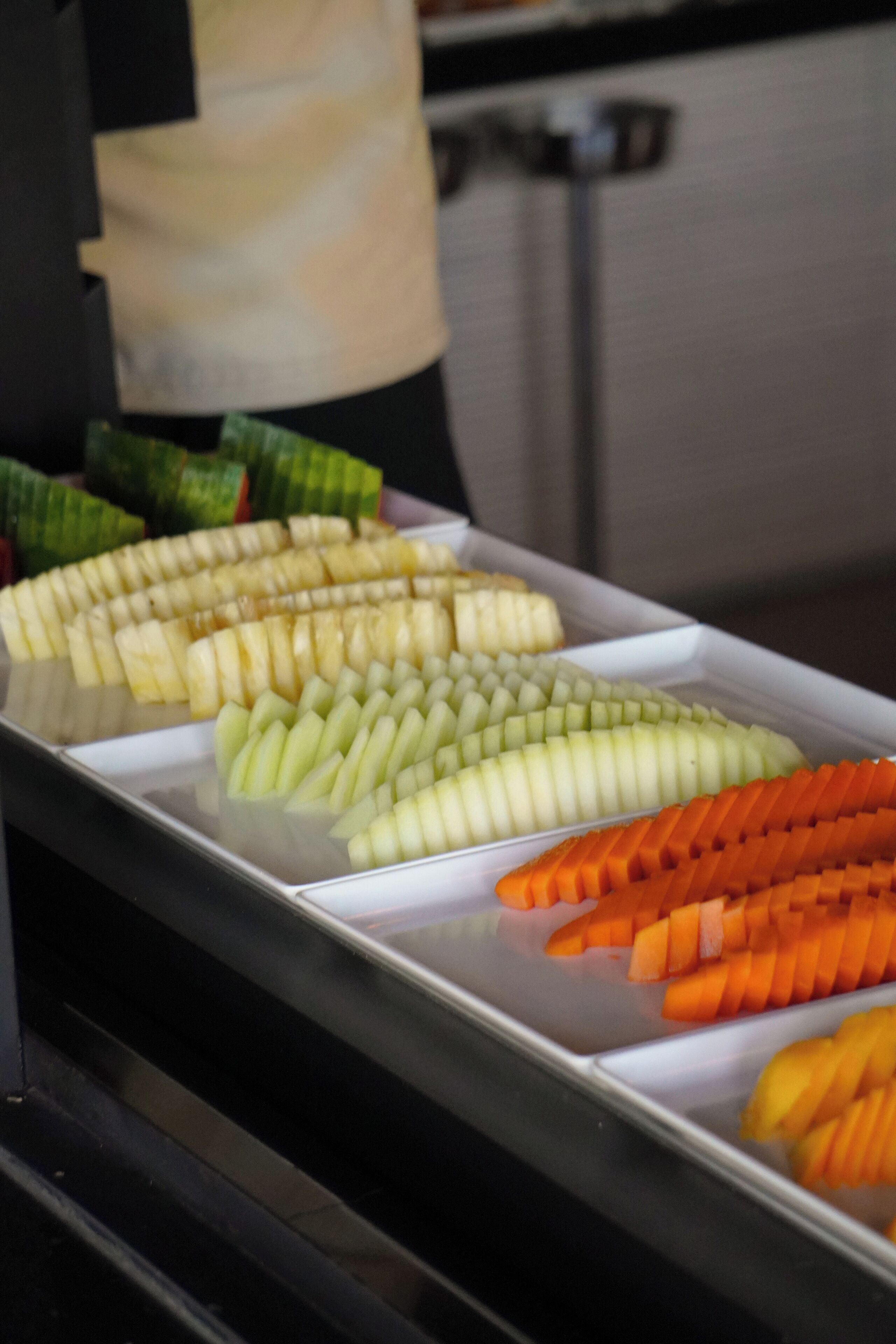 Un bufé con frutas y verduras cortadas y dispuestas con cuidado.