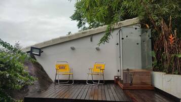 Una terraza en la azotea con dos sillas amarillas que dicen "Blonde" y un área de ducha con paredes de vidrio.