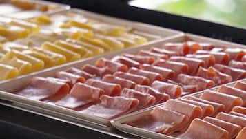 Un bufé con distintos alimentos, incluyendo carnes y quesos en porciones.