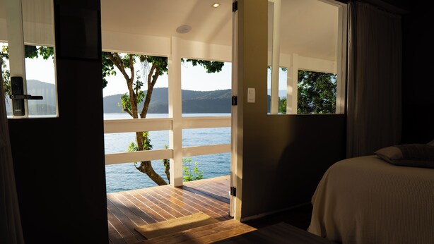 A bedroom with a large window overlooking a wooden deck and a lake. -  Pousada Papiro Boutique (Angra dos Reis)