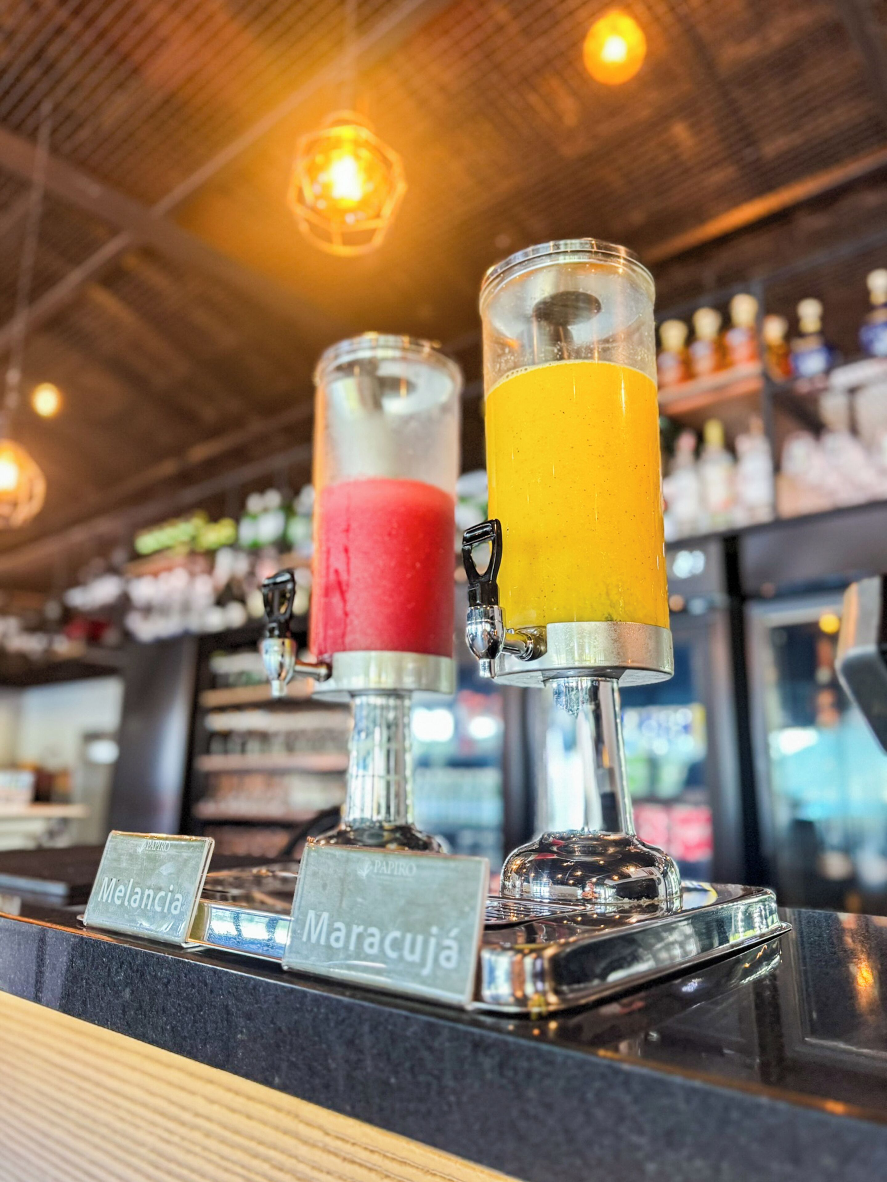 A bar area with two drink dispensers labeled "Melancía" and "Maracuja".