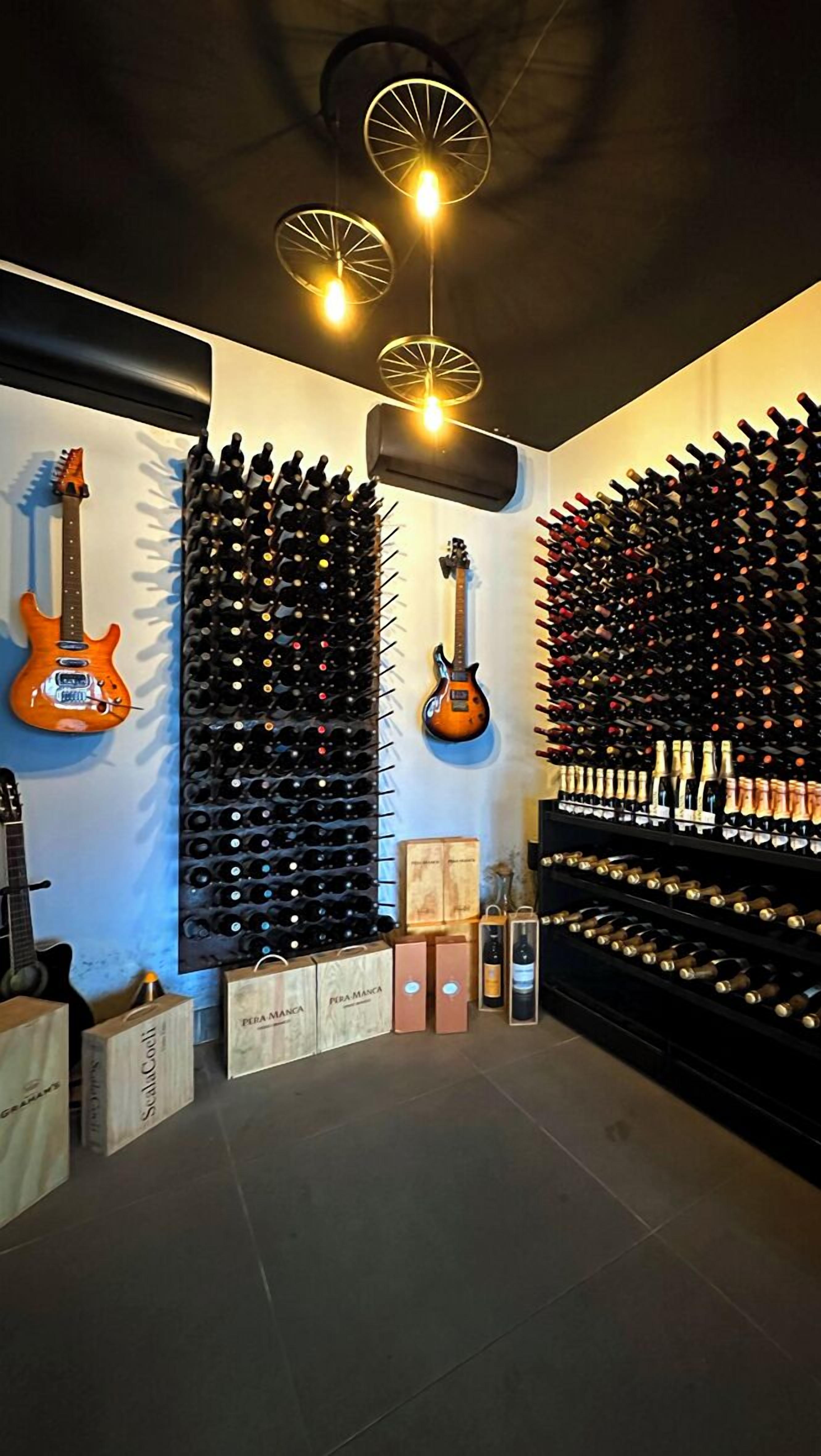 Una bodega con hileras de botellas de vino, dos guitarras y algunas cajas de vino.