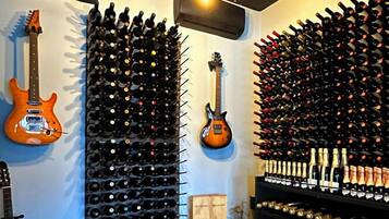 Una bodega con hileras de botellas de vino, dos guitarras y algunas cajas de vino.