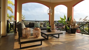 A spacious balcony with a sofa, coffee table, and potted plants.