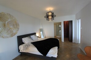 A modern bedroom with a large bed, a black headboard, and a unique wall art piece.