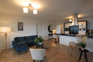 A modern living room with a sectional sofa, a coffee table, and a dining area with a chair and a small table.