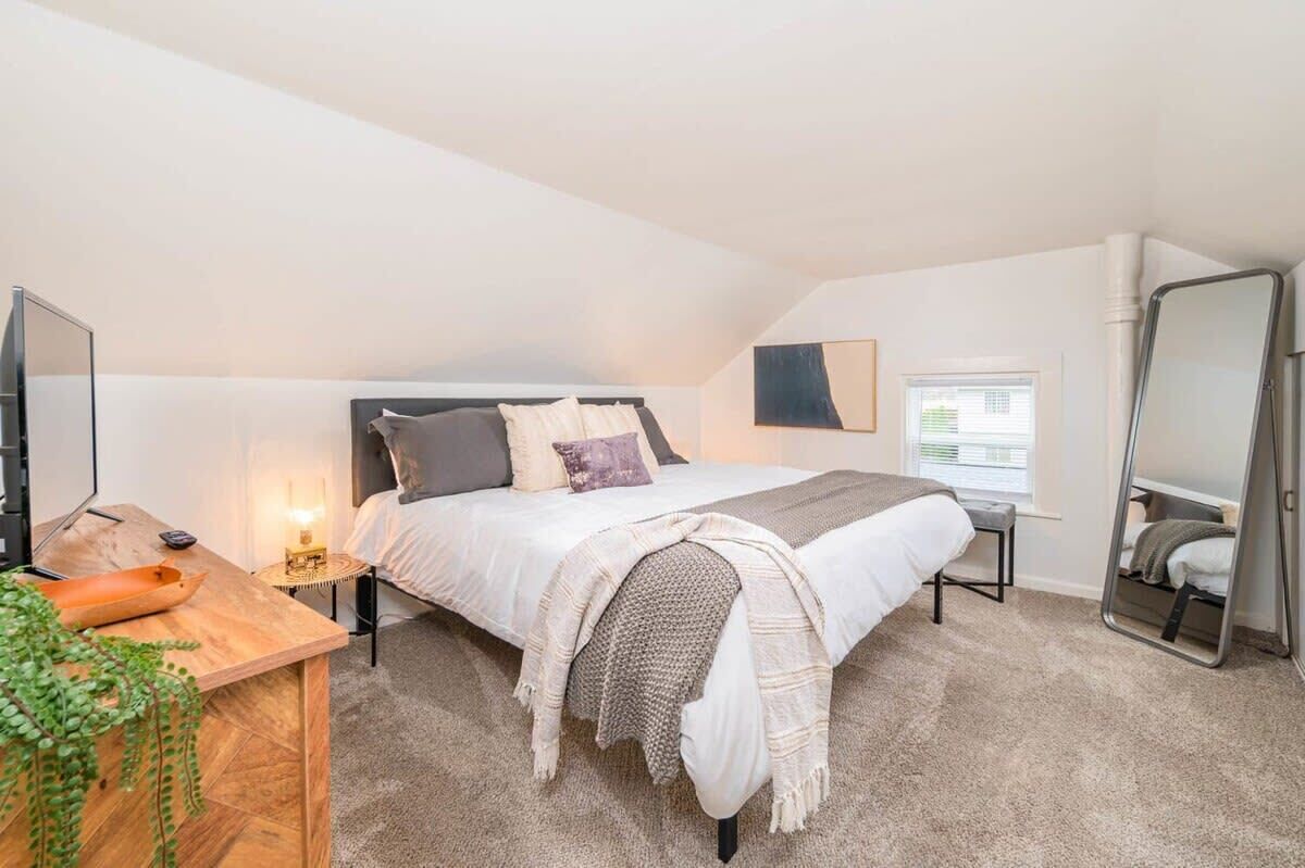 Ein Schlafzimmer mit Bett, Nachttisch, Lampe und Spiegel.