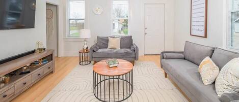 A living room with a grey sofa, a round coffee table, a TV, and a ceiling fan.