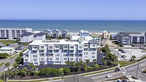 Een hotel aan de kust met meerdere verdiepingen, een parkeerplaats en uitzicht op de oceaan.