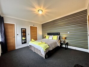 A bedroom with a bed, a nightstand, a mirror, and a door. - Le Morne- 5 Bed Luxury Coastal Retreat (Abergele)