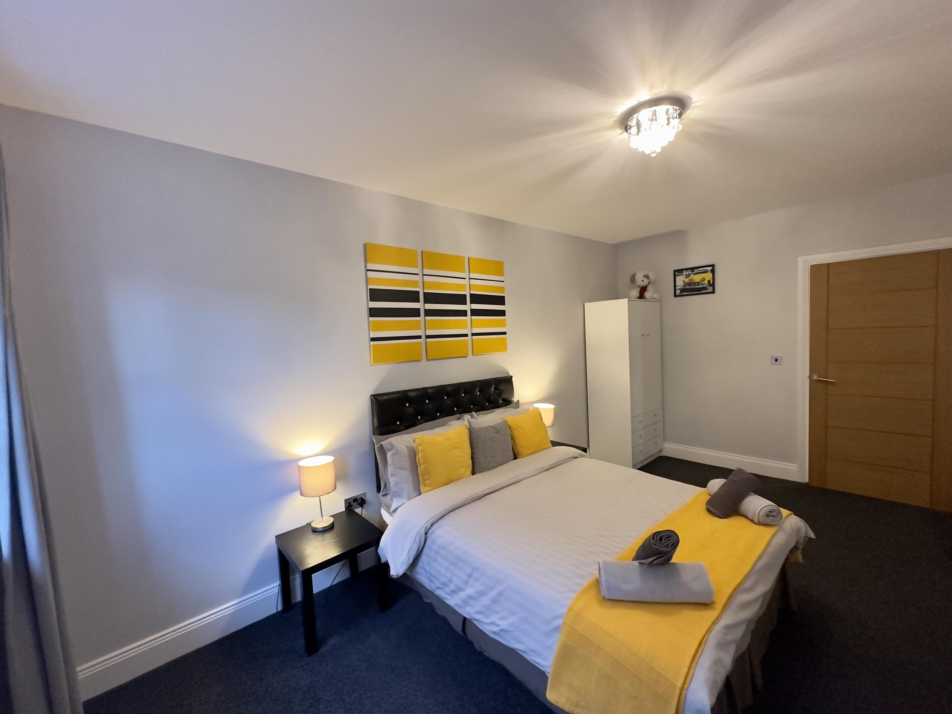A hotel room with a bed, a nightstand with a lamp, a wardrobe, and a door.