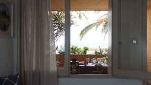 Une chambre avec vue sur la plage, un coin repas avec des chaises et une table, et une fenêtre avec des rideaux.