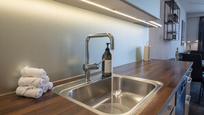 Una cocina moderna con un lavamanos de acero inoxidable, una encimera de madera y una pila de toallas blancas.