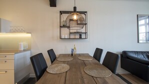 Un comedor con mesa de madera, sillas negras y lámpara colgante.