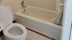 A bathroom with a bathtub, toilet, and a towel rack. - Downtown Inn #3- King Room (Asheville)