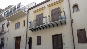 A building with multiple balconies, brown shutters, and a beige facade. - Jade House in the CENTER a stone's throw from the sea (Castellammare del Golfo)