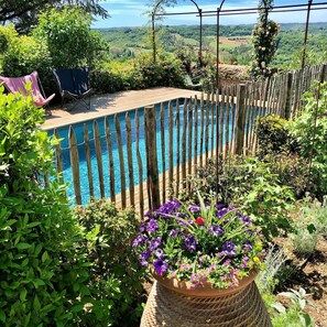A pool surrounded by a wooden fence, with a garden in the foreground. - La Dommerie - Charming cottage (Domme)