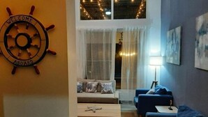 A cozy living room with a sofa, armchairs, and a coffee table. A ship's wheel with "WELCOME ABOARD" is on the wall. - VILLA BEACH HAPPY (Sosúa)