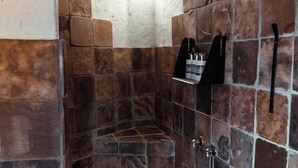 A shower area with stone tiles and a metal showerhead.