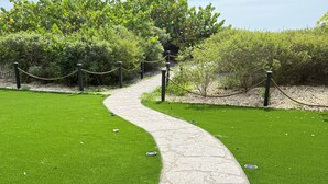 Uma trilha sinuosa em uma área ajardinada, com gramado verde e árvores.