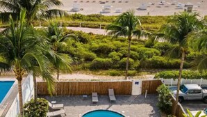 Uma área de piscina com espreguiçadeiras e vista para a praia.