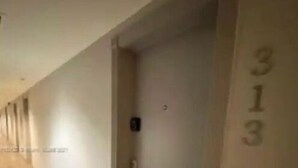 Corredor com piso de madeira e uma porta com o número 313.