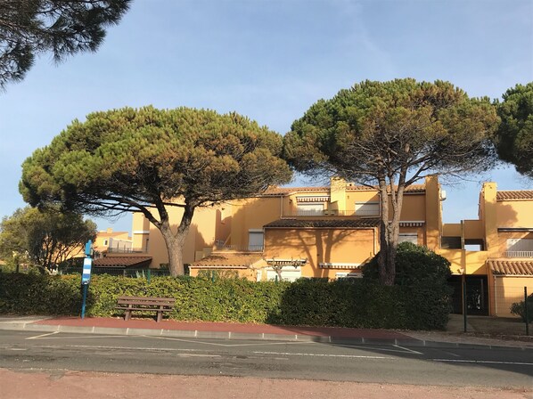 A yellow building with a balcony and a tree in front. - Studio Roquille Beach Area (le cap d'Agde)