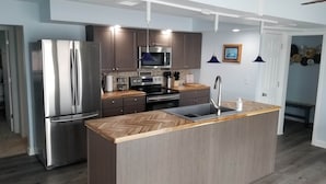 A modern kitchen with stainless steel appliances, a herringbone-patterned countertop, and pendant lighting. - RIVER FRONT RELAXATION (Chillicothe)