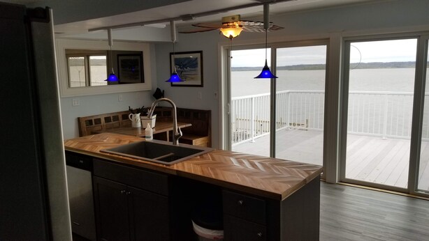 A modern kitchen with a wooden countertop, a sink, and a view of a balcony with a railing. - RIVER FRONT RELAXATION (Chillicothe)