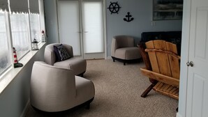 A living room with a beige armchair, a wooden chair, and a window with a view of a dock. - RIVER FRONT RELAXATION (Chillicothe)