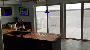 A modern kitchen with a large window and sliding doors leading to a deck with a view of a body of water. - RIVER FRONT RELAXATION (Chillicothe)