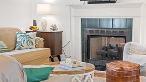 Un salon chaleureux avec une cheminée, un canapé, une table basse et un téléviseur.