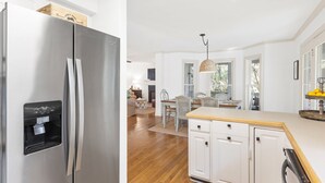 Une cuisine moderne avec un réfrigérateur en acier inoxydable, des meubles blancs et une table à manger en bois.