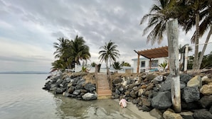 A beachside property with a clear view of the sea, a wooden staircase leading to a covered area, and palm trees. - NEW LISTING! OCEAN FRONT AND RAINFOREST 16 GUESTS (Río Grande)