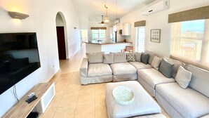 A spacious living area with a large L-shaped sectional sofa, a flat-screen TV, and a ceiling fan. - NEW LISTING! OCEAN FRONT AND RAINFOREST 16 GUESTS (Río Grande)