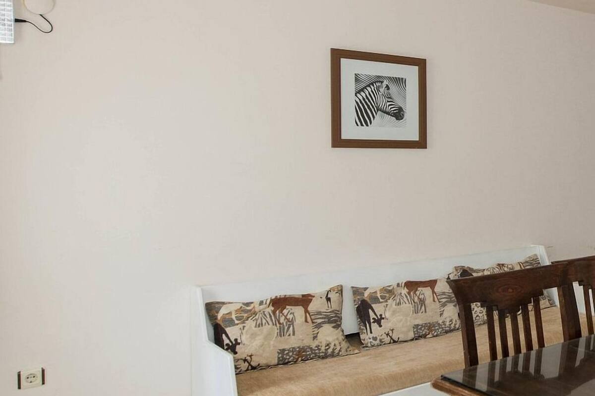 A room with a white sofa, a framed zebra artwork on the wall, and a dining table with chairs.