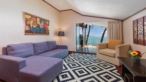 A living room with a purple sofa, beige armchair, and a patterned rug. A painting is on the wall, and there's a view of the sea through a glass door. - Your exclusive villa on the sand, Private Pool, Stunning Ocean Views (Tambon Patong, Amphoe Kathu)