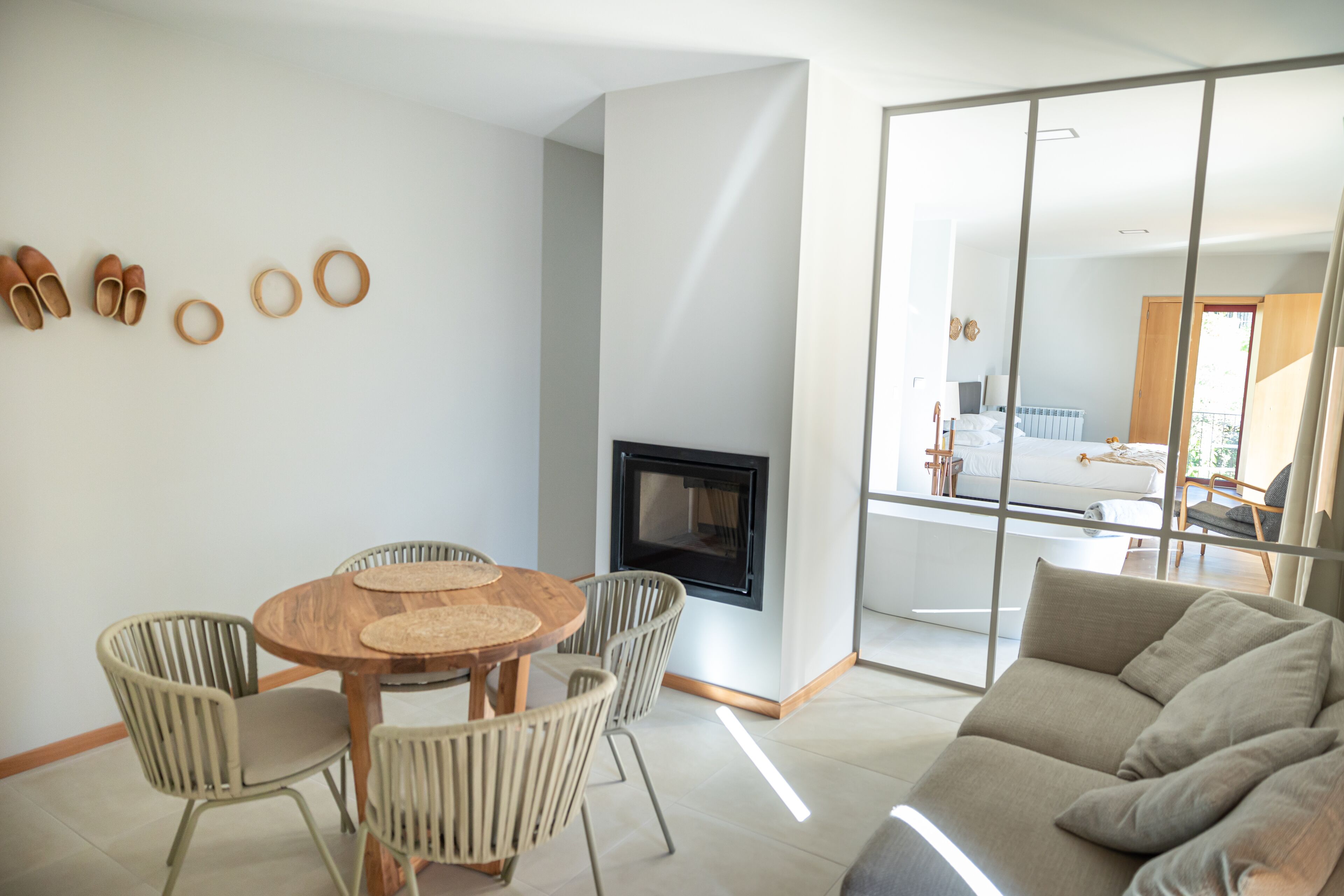 A modern living room with a round wooden table, wicker chairs, a sofa, and a fireplace.