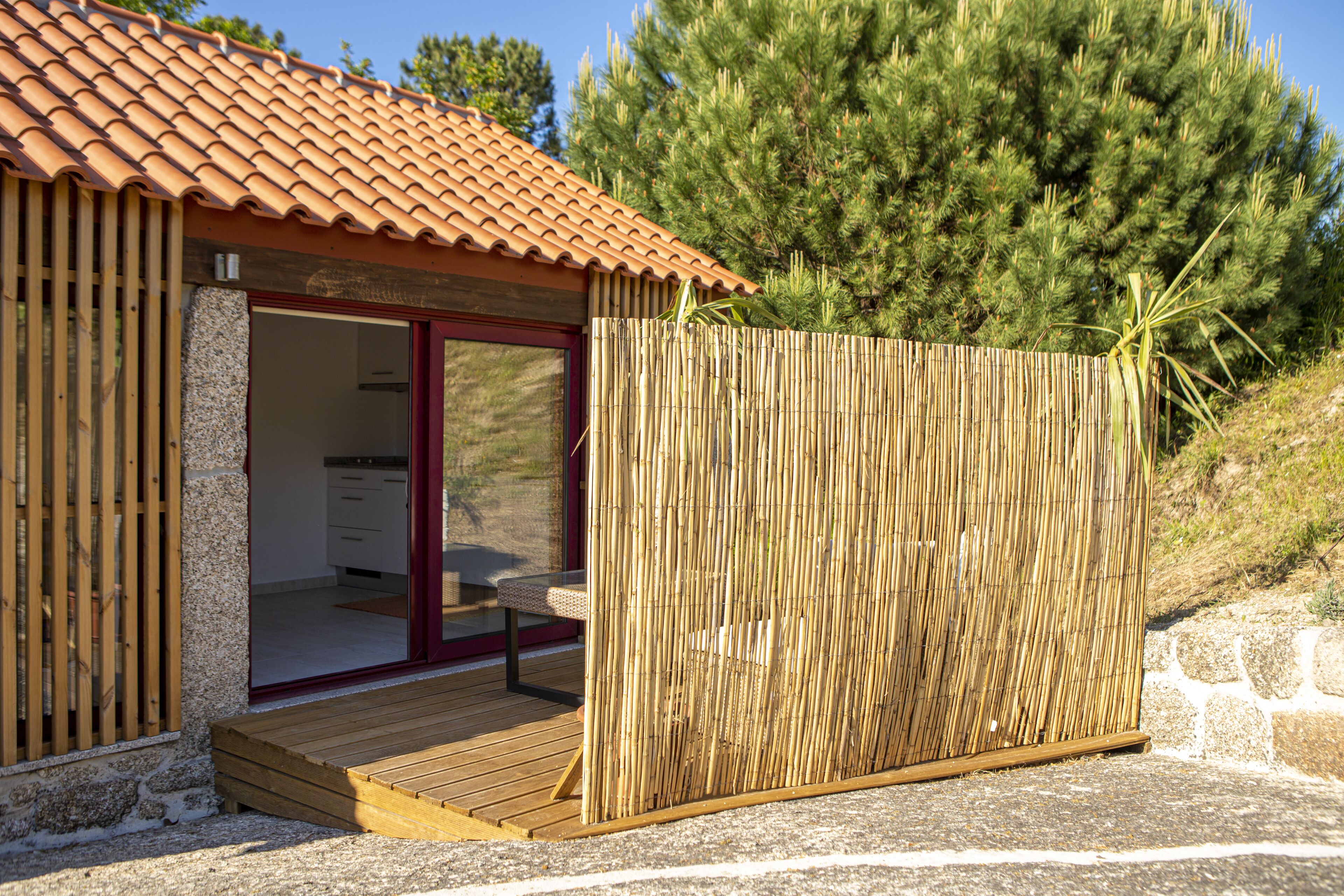 A small wooden building with a tiled roof, a bamboo fence, and a wooden deck.