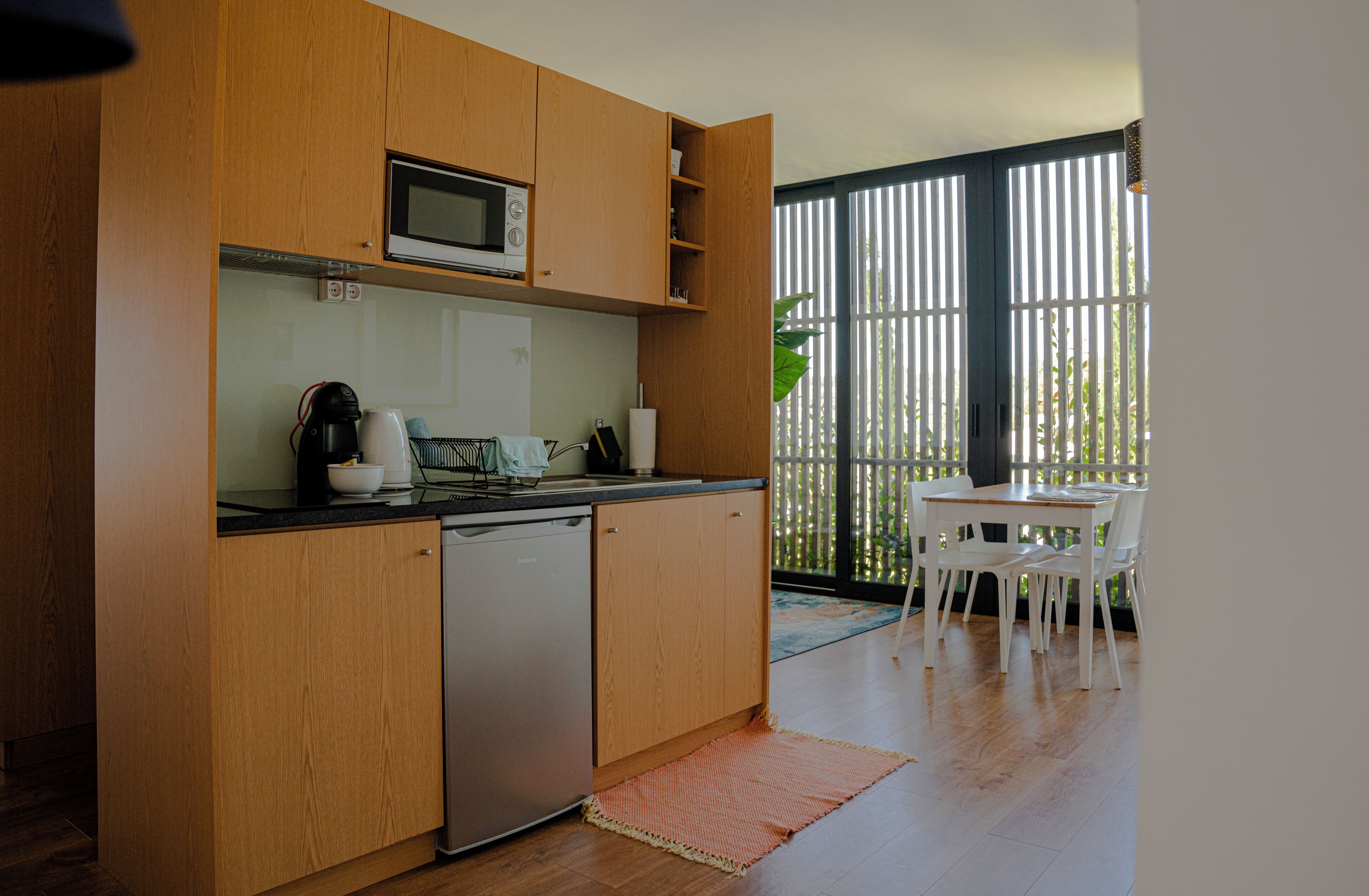 Una cocina compacta con armarios de madera, lavavajillas y microondas.