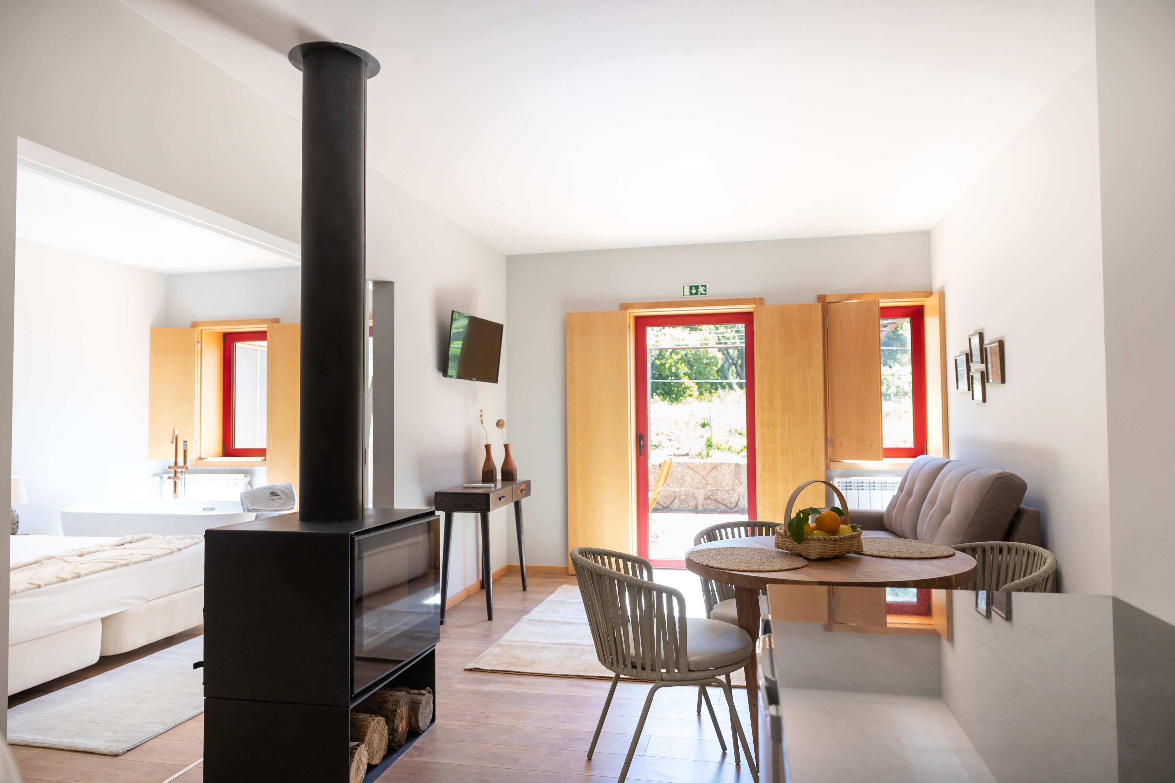 A modern living room with a fireplace, a dining area with chairs, a sofa, and a television on the wall.