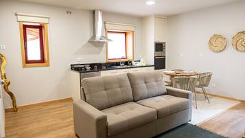 Una cocina moderna con horno integrado, un comedor con mesa y sillas redondas, y un sofá en la sala de estar.