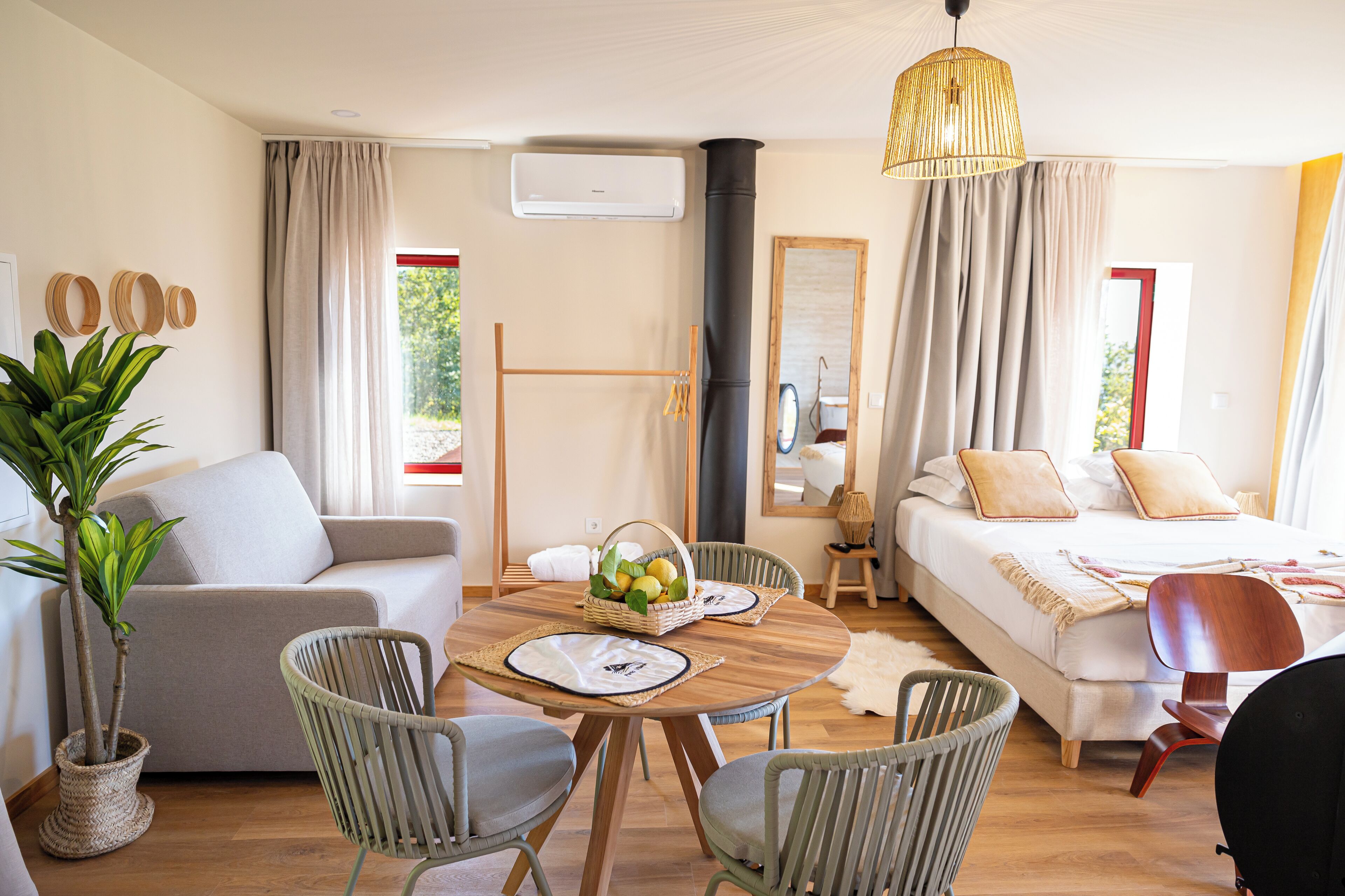 Een moderne hotelkamer met een bank, eettafel, stoelen, een bed en een grote spiegel.